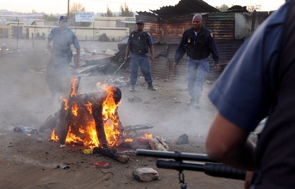 Varios policías intentan apagar el fuego que consume a uno de los refugiados.