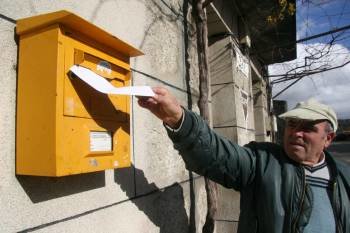 Un hombre deposita una carta en un buzón de Correos, en una zona rural de la provincia. (Foto: XESÚS FARIÑAS)