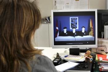 Una joven observa el video de ETA, en el que los tres encapuchados están flanqueados por las banderas del País Vasco y Navarra. (Foto: ABIR SULTAN)