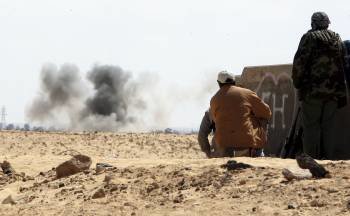 Soldados rebeldes observan el humo de los combates en la carretera que une Ajdabiya y Bengasi. (Foto: HALED ELFIQI)