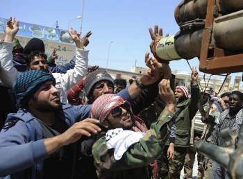 Rebeldes libios cargan un lanzamisiles en los combates que mantienen en las prisimidades de Brega. (Foto: VASSIL DONEV)