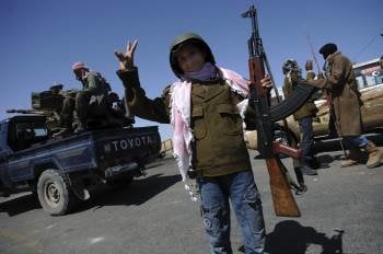 Un niño libio de diez años posa con un fusil en un puesto de los rebeldes cerca de Brega. (Foto: VASSIL DONEV)