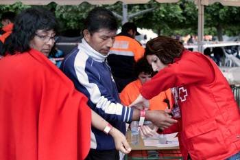 Una voluntaria de Cruz Roja pone una pulsera a un afectado. (Foto: J.F. MORENO)