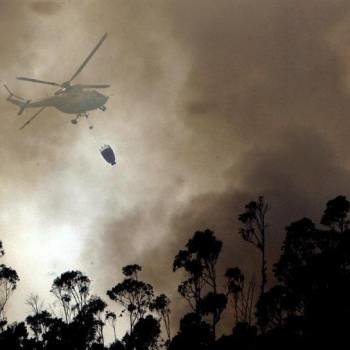 Un helicóptero descarga agua sobre uno de los frentes del incendio forestal en Boiro. Foto: Xoan Rey