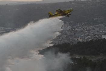 Un avión arroja agua sobre las llamas. Al fondo, el casco urbano de la ciudad. (Foto: MIGUEL ÁNGEL)