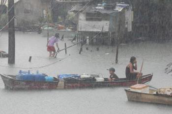  Filipinos recorren las vías inundadas tras el paso del tifón Nock-Ten (Foto: EFE)