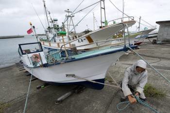 Un pescador asegura su bote ante la llegada del tifón Roke. (Foto: EFE)