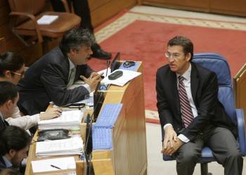 El presidente de la Xunta de Galicia, Alberto Núñez Feijoo (d), conversa con el diputado del PP Pedro Puy durante la sesión plenaria en el Parlamento. (Foto: EFE)