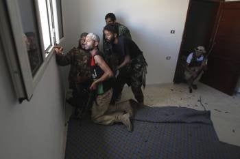 Tiradores rebeldes libios intentan localizar enemigos durante los combates que se libran en la ciudad de Sirte (Foto: EFE)