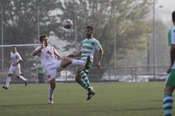 El jugador del Covadonga Jhonny levanta el balón ante el lateral del Melias Gabri (Foto: MIGUEL ÁNGEL)