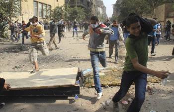 Manifestantes egipcios corren para huir del gas lacrimógeno durante un enfrentamiento con las fuerzas de seguridad del estado en El Cairo (Foto: EFE)