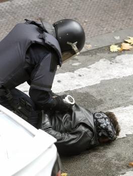 Un policía nacional esposa a una de las personas que hoy querían evitar el desahucio de una familia de Torrejón de Ardoz (Foto: EFE)