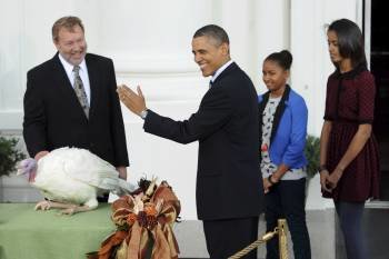 El presidente estadounidense, Barack Obama (2i), 'indulta' al pavo 'Liberty' en presencia de sus hijas, Sasha (2d) y Malia (d), y del presidente de la Federación Nacional del Pavo, Richard Huisinga (i). 