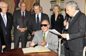 -El rey firma wen el libro dehonor de la Fundación Carlos de Amberes junto al presidente de la misma, Miguel Ángel Aguilar (d), entre otros, durante la inauguración de la exposición la Orden del Toisón de oro, esta tarde en la Fundación Carlos de Amberes.