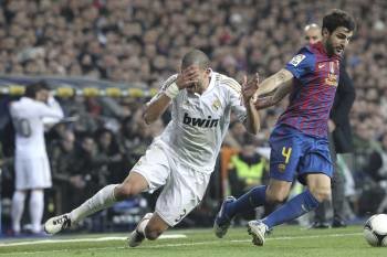 El jugador del Real Madrid Pepe cae ante Cesc Fábregas