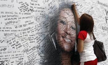 Una joven firma en un mural con la foto de Whitney Houston en Manila (Filipinas). (Foto: ARCHIVO)