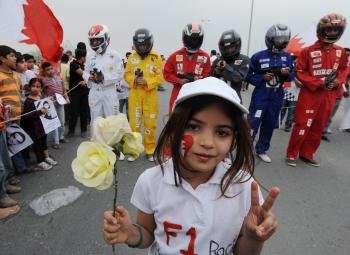 Una joven manifestante sostiene una rosa y compañeros de protesta vestidos como pilotos de la Fórmula Uno usando armas de juguete (Foto: EFE)