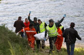 Agentes de la Guardia Civil y miembros de Protección Civil retiran el cadáver del río y lo trasladan a la orilla para ser enviado al CHUO. (Foto: XESÚS FARIÑAS)