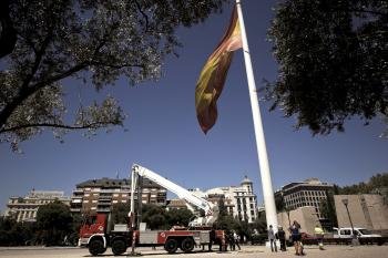 Operarios municipales y miembros de la Armada junto a la grúa que ha ayudado a izar la bandera española de grandes dimensiones que ondea en los Jardines del Descubrimiento, en la plaza de Colón de Madrid (Foto: EFE)