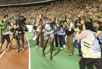 Bolt lanza una de las zapatillas al término de la carrera. (Foto: JULIEN WARNARD)