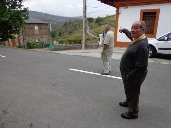 Dos vecinos de Portela muestran la carretera OU-533, a la que fue trasladada la parada de autobús. (Foto: J.C.)