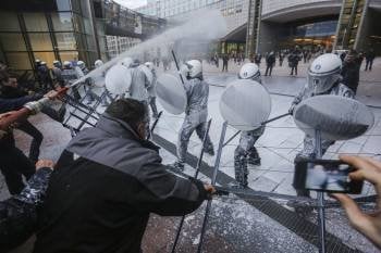 Un grupo de agricultores belgas rocía con leche a agentes antidisturbios en Bruselas. (Foto: J. WARNAND)