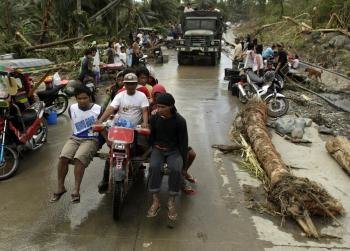 Un grupo de habitantes de New Bataan, en una de las carreteras inundadas al paso del tifón 'Bopha'