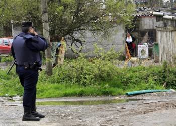 Un agente de Policía vigila el asentamiento situado en Freixeiro, en el concello coruñés de Narón. (Foto: KIKO  DELGADO)