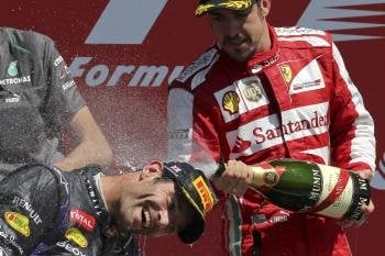 Fernando Alonso riega con champán al australiano Webber en el cajón del GP de Inglaterra. (Foto: Valdrin Xhemaj)