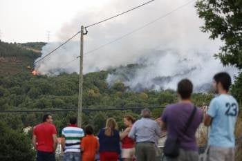 Vecinos de Pombar siguen la evolución de las llamas en los montes cercanos a la aldea. (Foto: XESÚS FARIÑAS)
