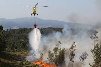 Uno de los helicópteros arroja agua sobre el fuego.