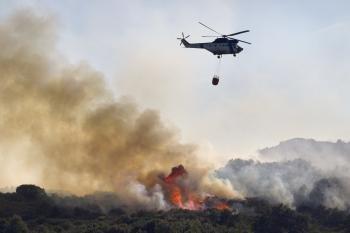 Un helicóptero se dispone a lanzar agua sobre el incendio de Xinzo de Limia. (Foto: EFE)