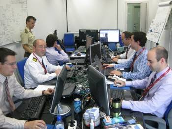 Un grupo de militares y funcionaros civiles trabajan ante la pantalla del ordenador.
