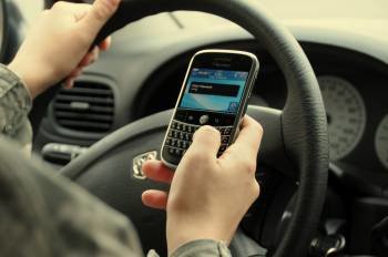 Una joven activa su teléfono móvil mientras conduce su vehículo. 