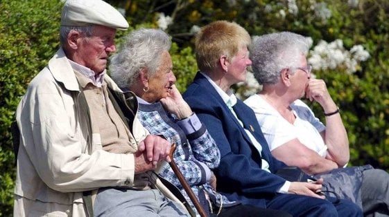 Un grupo de personas mayores descansa en el banco de un parque