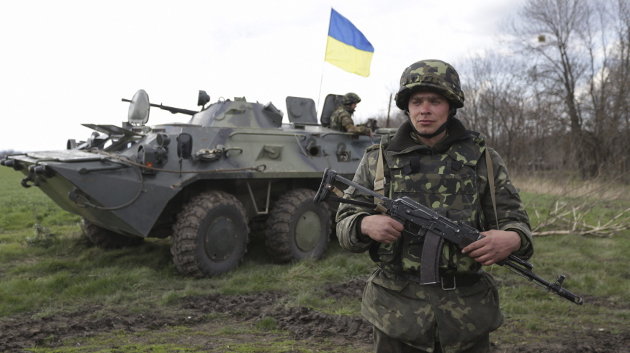 Una soldado ucraniano vigila en una zona cerca de un vehículo militar