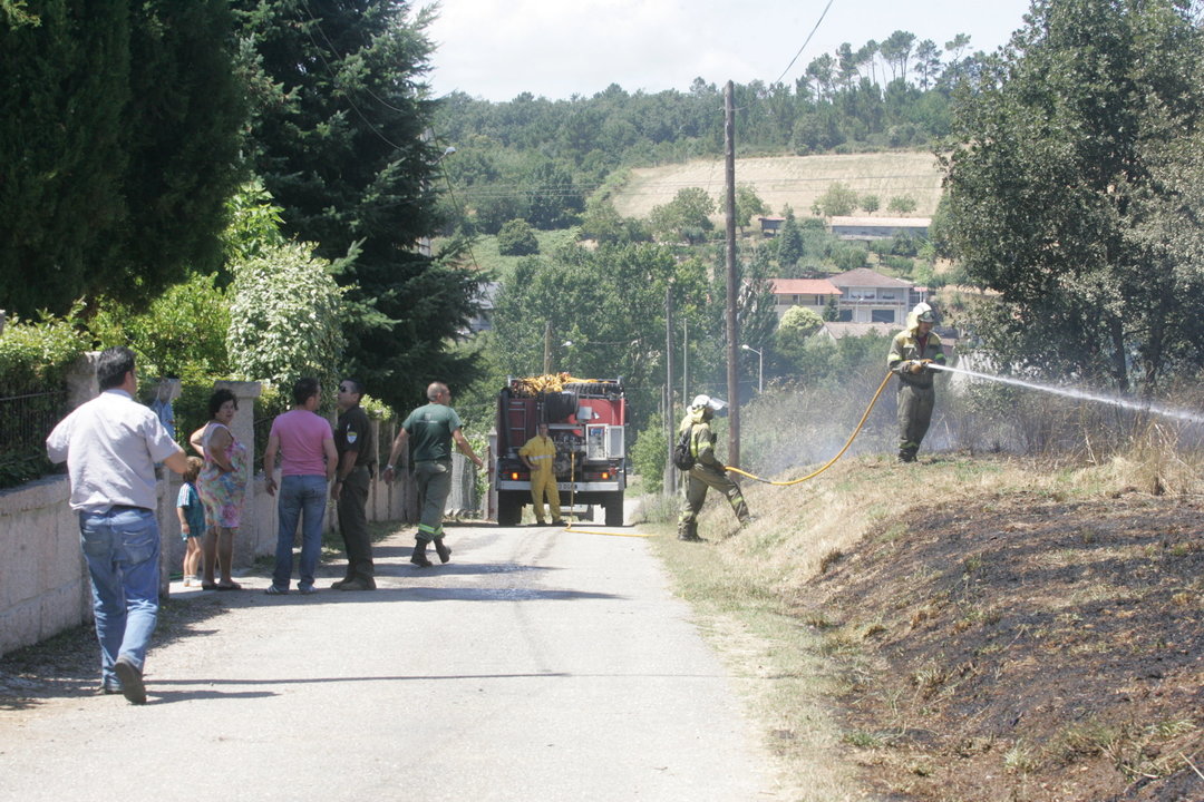 Los bomberos, apagando maleza en el arcén de la carretera que conduce al pueblo de A Barxa (MARCOS ATRIO)