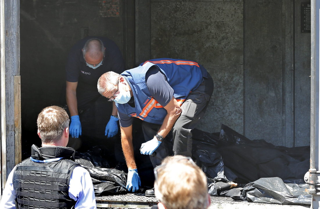 Expertos forenses holandeses conversan con inspectores de la OSCE mientras revisan las bolsas de los cadáveres de las víctimas del vuelo MH17 