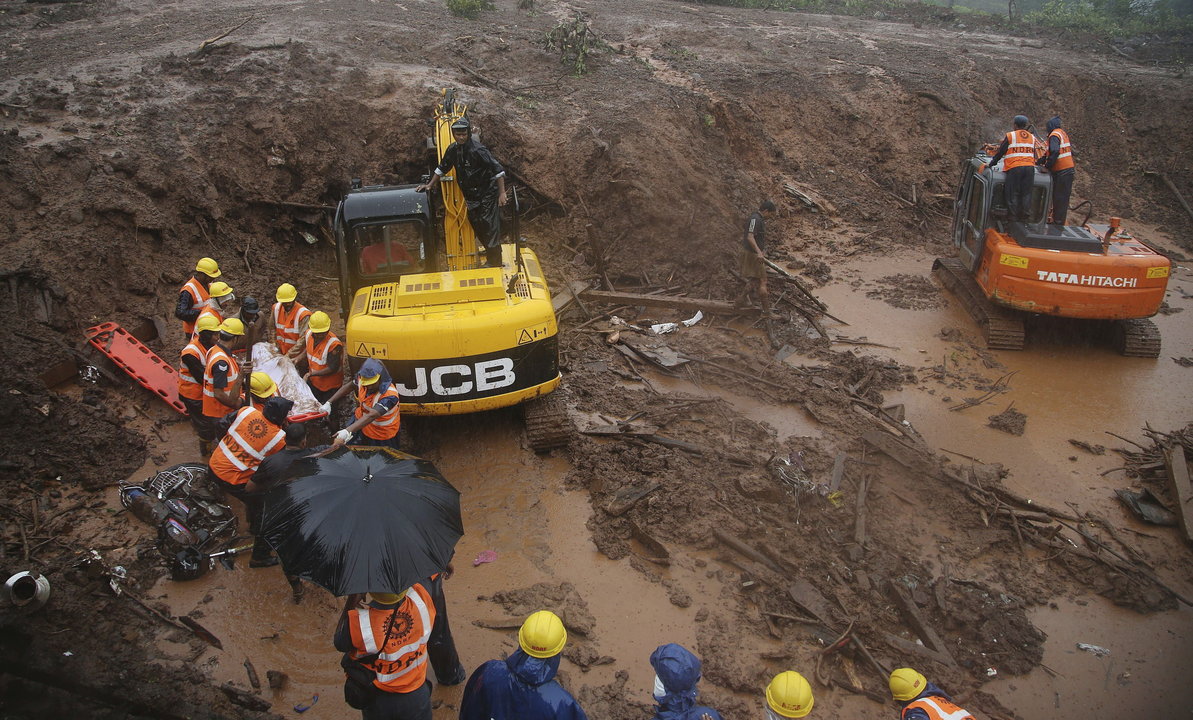 Miembros de los servicios de rescate indios evacúan el cadáver de una de las víctimas tras el corrimiento de tierra en la localidad de Malin 