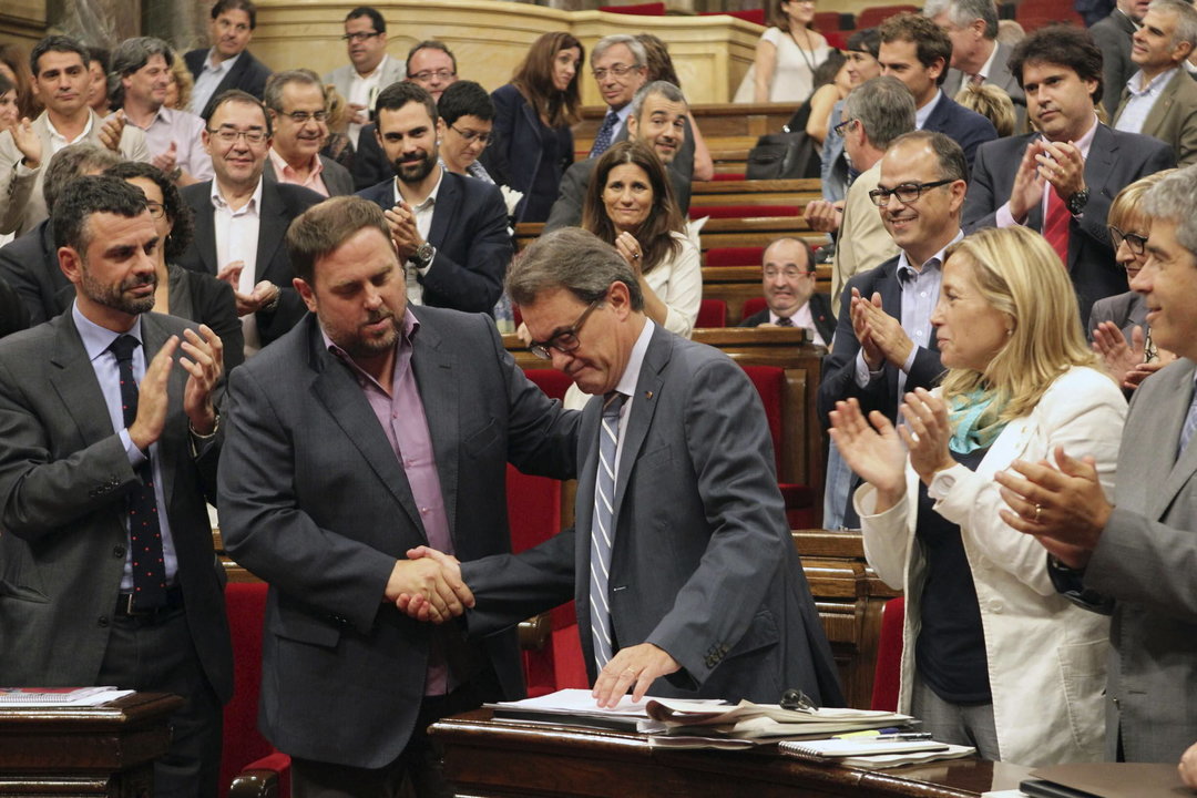El presidente de la Generalitat, Artur Mas (c), estrecha la mano del lider de ERC, Oriol Junqueras (2i), ante el aplauso de sus compañeros de partidos, tras la aprobación