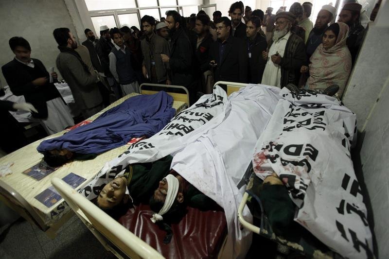 Familiares y miembros de los servicios de emergencia congregados junto a los cadáveres de los alumnos asesinados en el ataque talibán contra una escuela militar, en un hospital de Peshawar