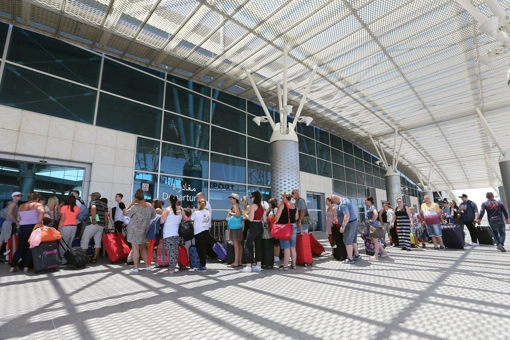 Un numeroso grupo de turistas británicos hace cola en el exterior del aeropuerto de Susa para abandonar el país.