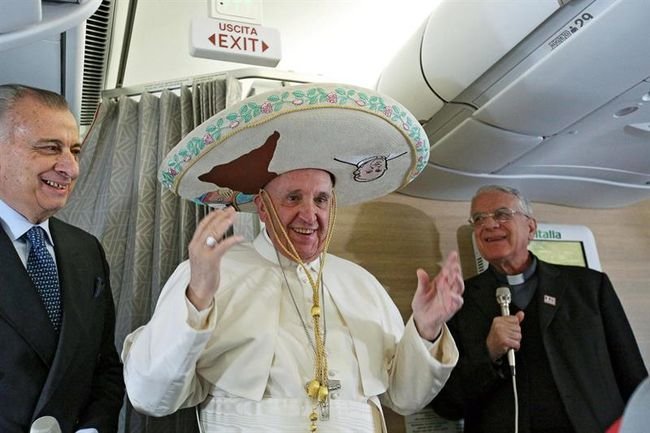 El papa Francisco (c) posa con un sombrero mexicano a bordo del avión que le llevará hasta la Habana.
