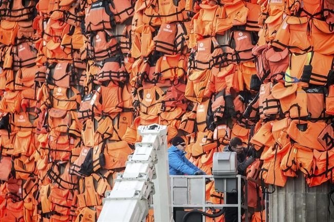 Dos empleados colocan chalecos salvavidas utilizados por refugiados en la fachada del Konzerthaus como parte de la instalación del artista chino Ai Weiwei.