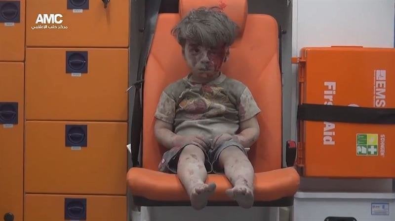 un niño herido de 5 años, sentado en una ambulancia tras ser rescatado anoche de una vivienda bombardeada en el barrio de Al Qatergui en la ciudad siria de Alepo
