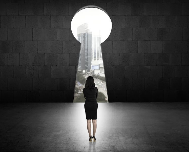 Concept of success business woman looking through key hole