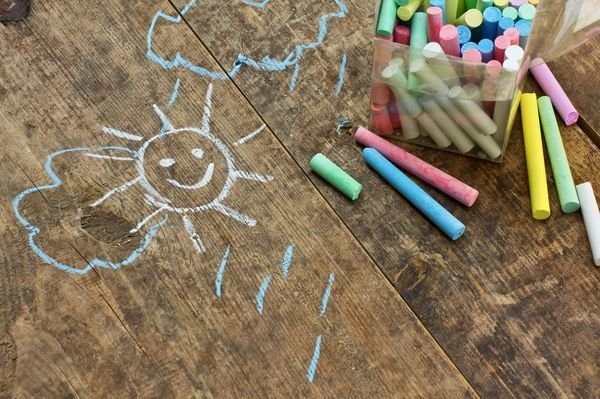 Child's drawings and coloured chalk on wooden background