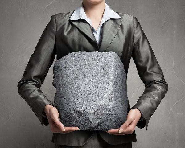 Close view of businesswoman holding big heavy stone