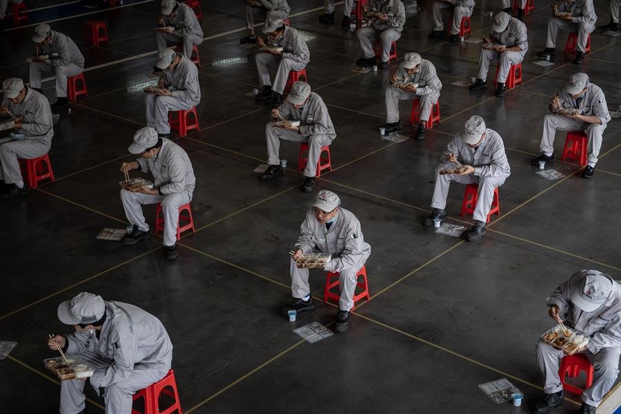 Trabajadores en Wuhan realizan su descanso para comer manteniendo la distancia de metro y medio. (Foto: EFE)