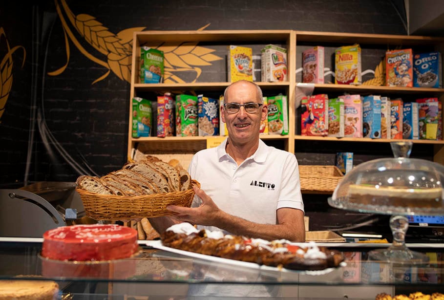 Julio Alén con una cesta de su pan, algunas de sus dulces propuestas y un amplio surtido de cereales de fondo (XESÚS FARIÑAS).